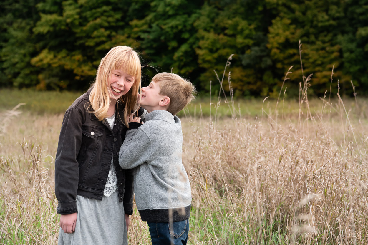 Boy whispering to sister. Livonia photographer near me