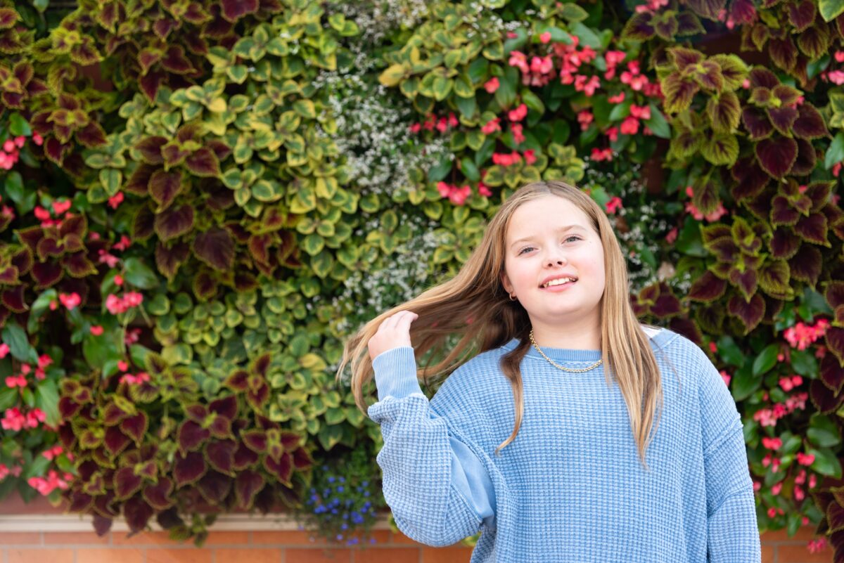 gorgeous teen flipping her hair in front of plant wall northville photography session